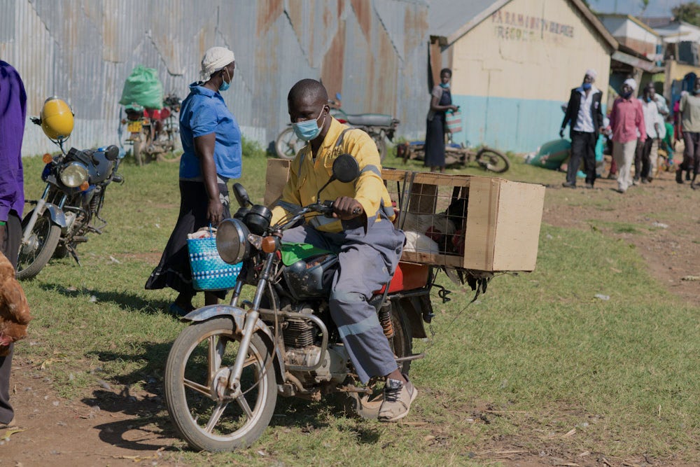 A man drives a motorbike through a crowded area in Kenya.