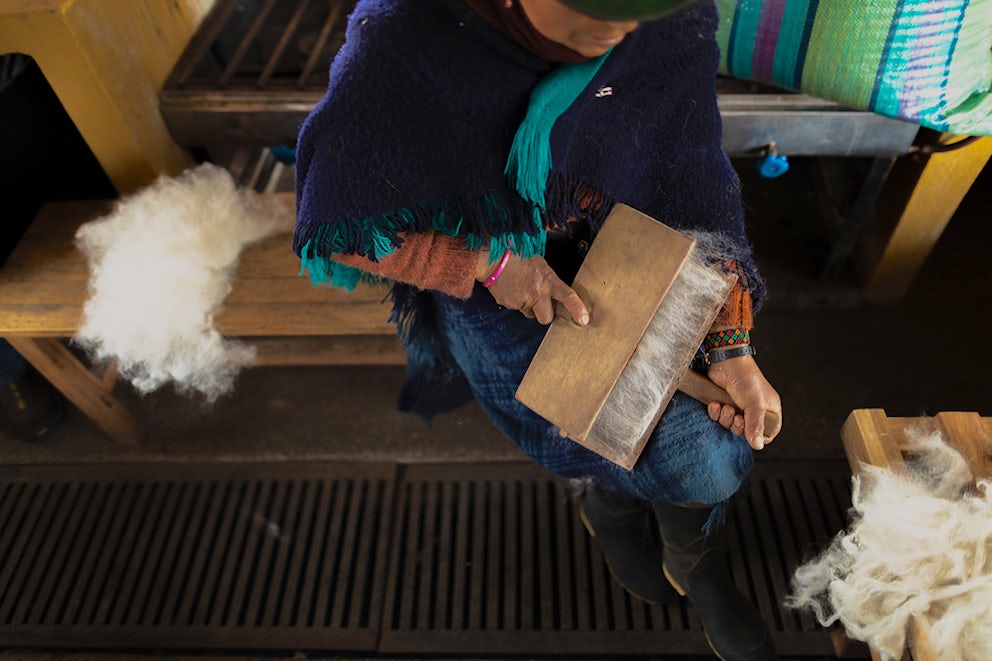A woman cards alpaca fiber so that it can be spun into yarn