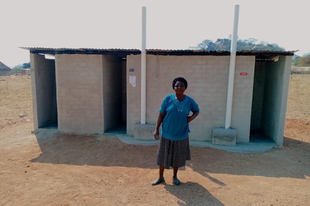 Emilia Tumbe stands in front of the bathroom she built her family after their latrine was destroyed by Cyclone Idai.