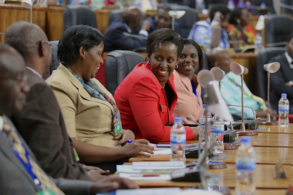 Three women sit at their parliamentary seats and discuss something together.