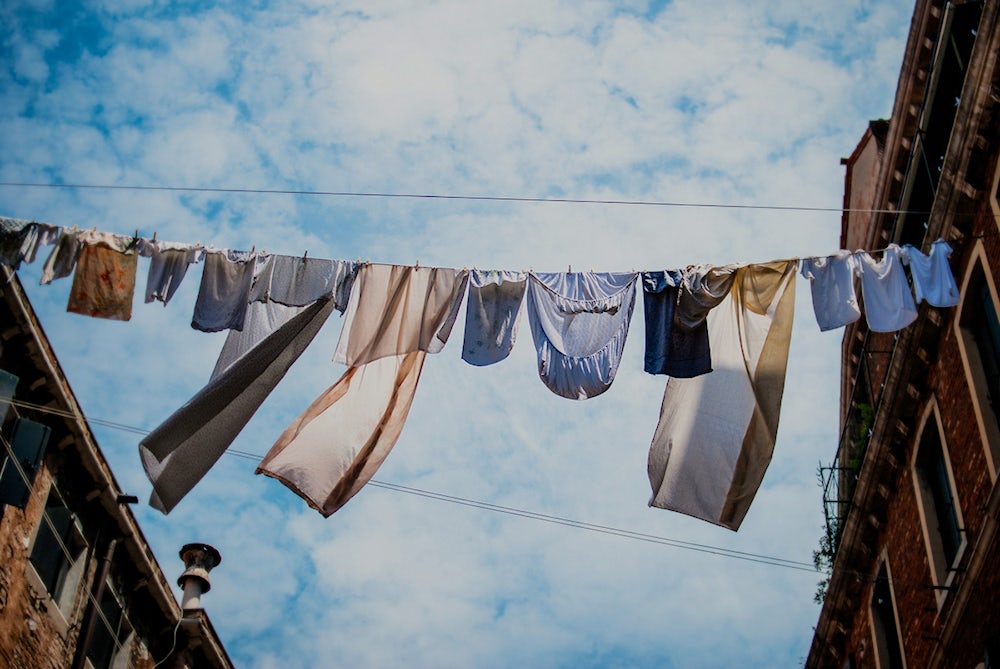 Laundry hanging on a clothesline strung between two buildings.