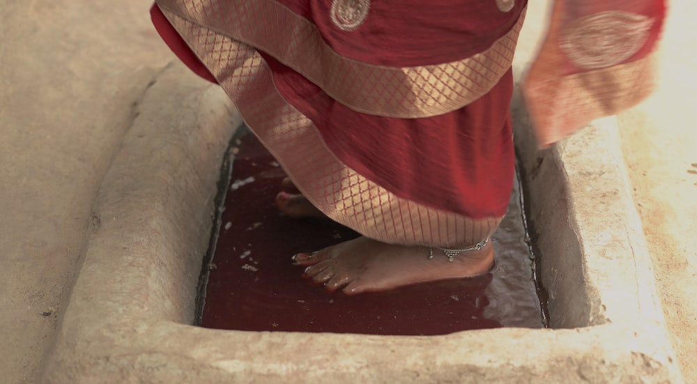 A close up shot of two feet in a purple disinfecting liquid.