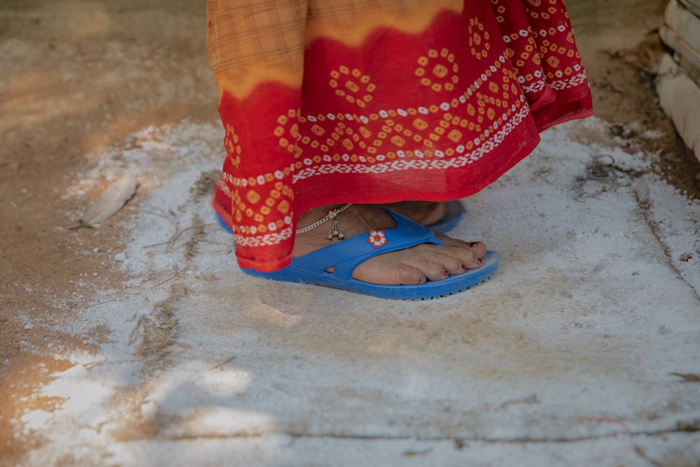 A close up shot of a woman's feet standing on a mat coated in lime, a dusty white powder.