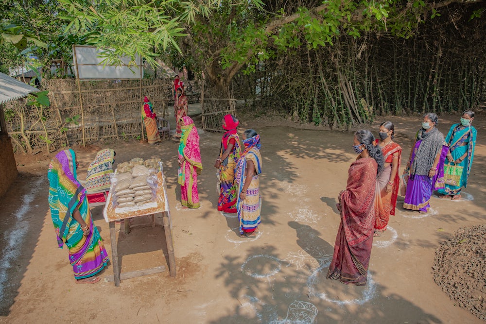 Women stand six feet apart from each other and wear face masks to prevent the spread of disease.