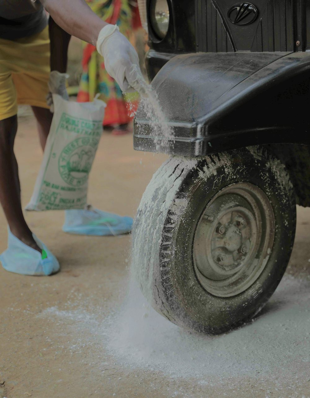 A man dusts a white powder, lime, onto his vehicle's wheels.