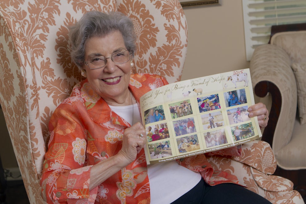 A smiling woman in her 70s holds up a photo collage from Heifer International.