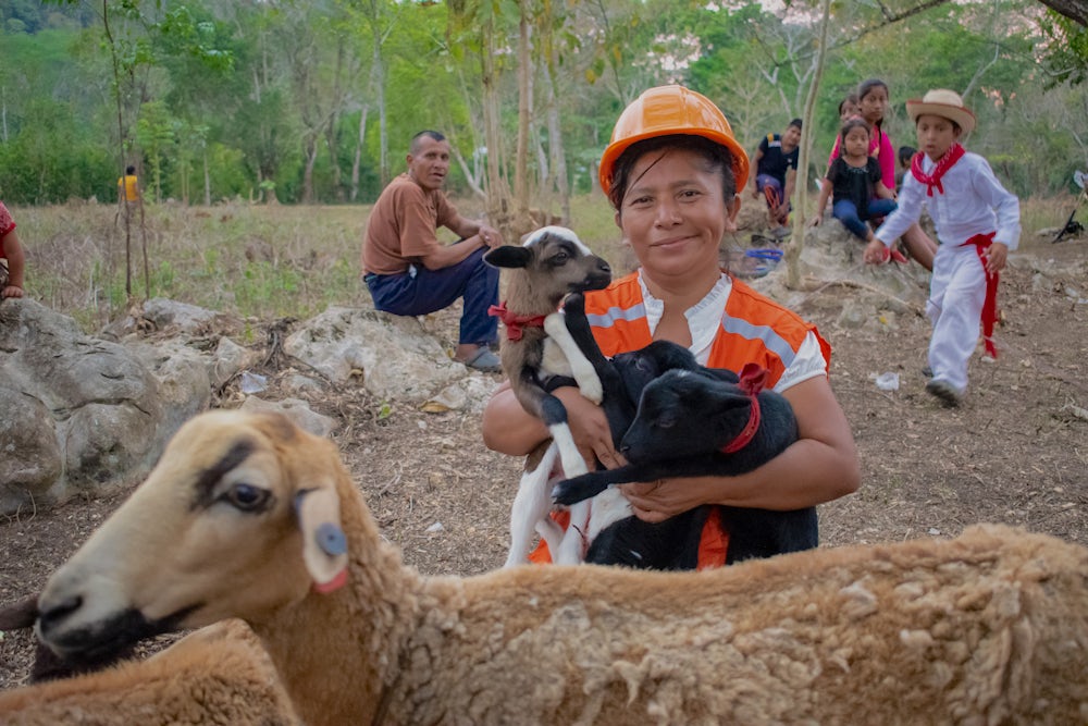 Maria Louisa Vasquez Gabriel holds three lambs in her arms.