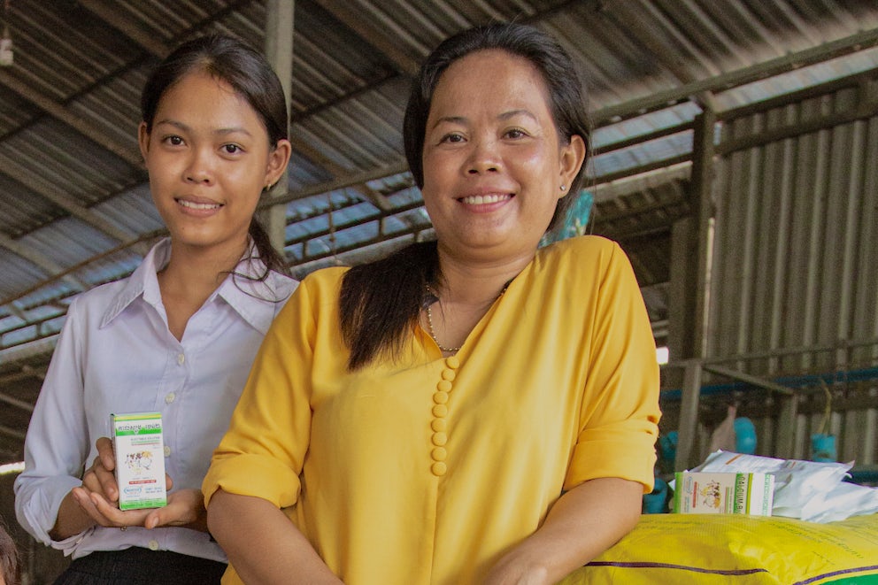 Hoy Lin, a young Cambodian woman in a yellow shirt, poses with her daughter who is holding one of their store's products.