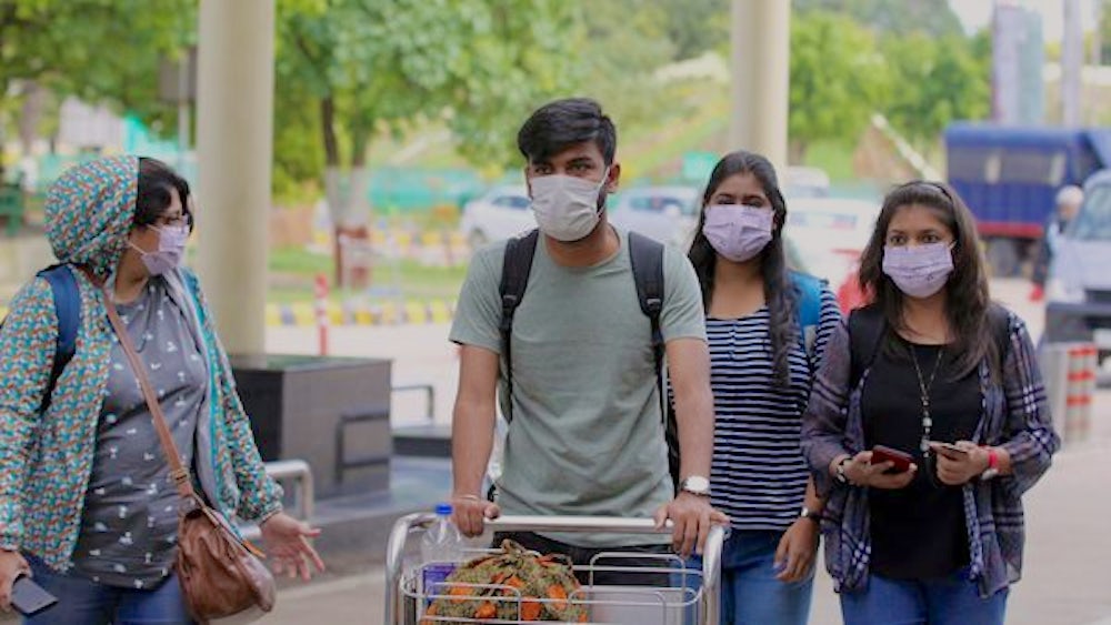 People at an airport wear protective masks.