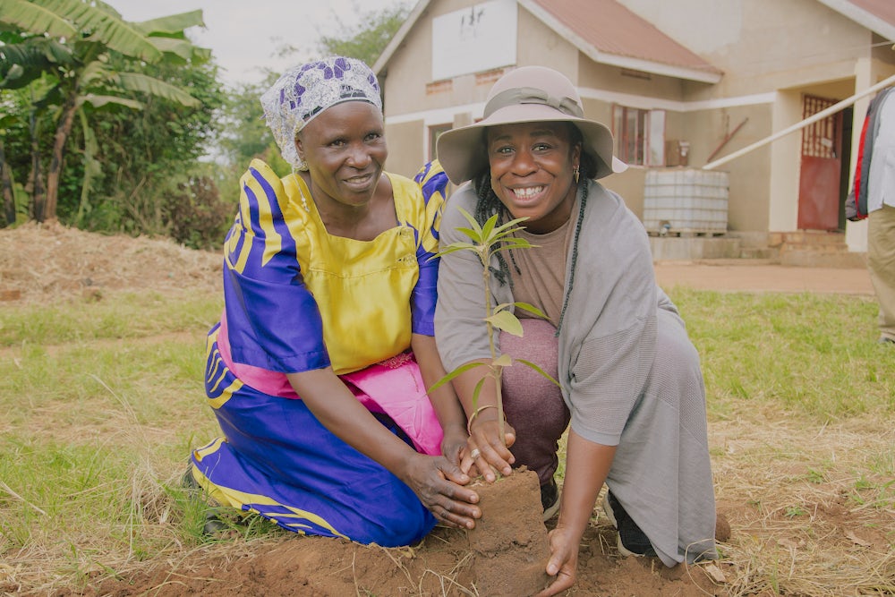 Aduba helps plant a mango tree.