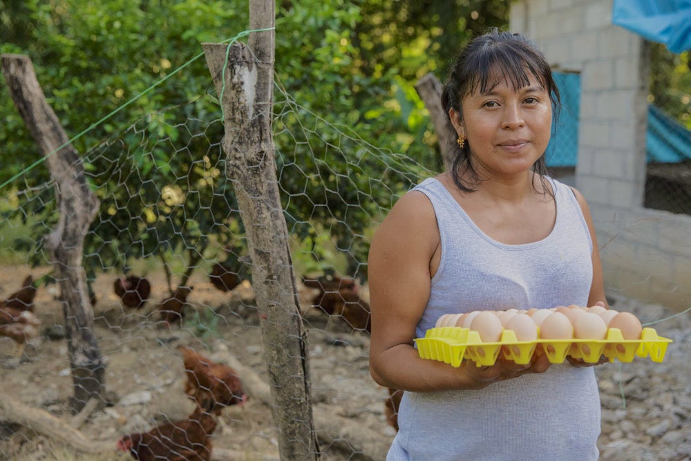 A woman holds a tray of eggs at her poultry farm.