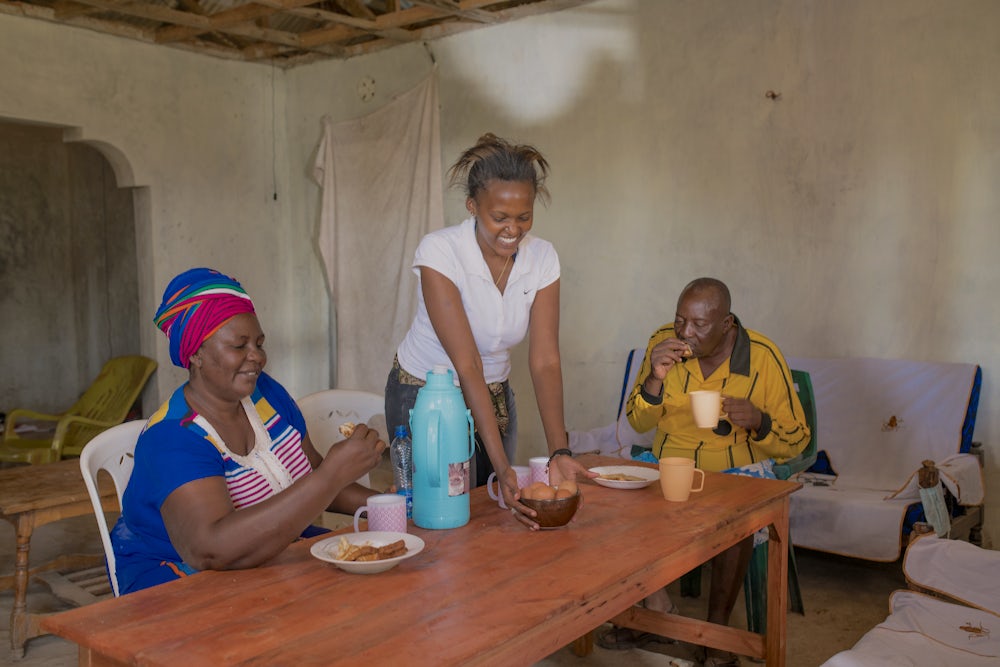 A woman, her daughter and her husband sit at a table eating eggs.