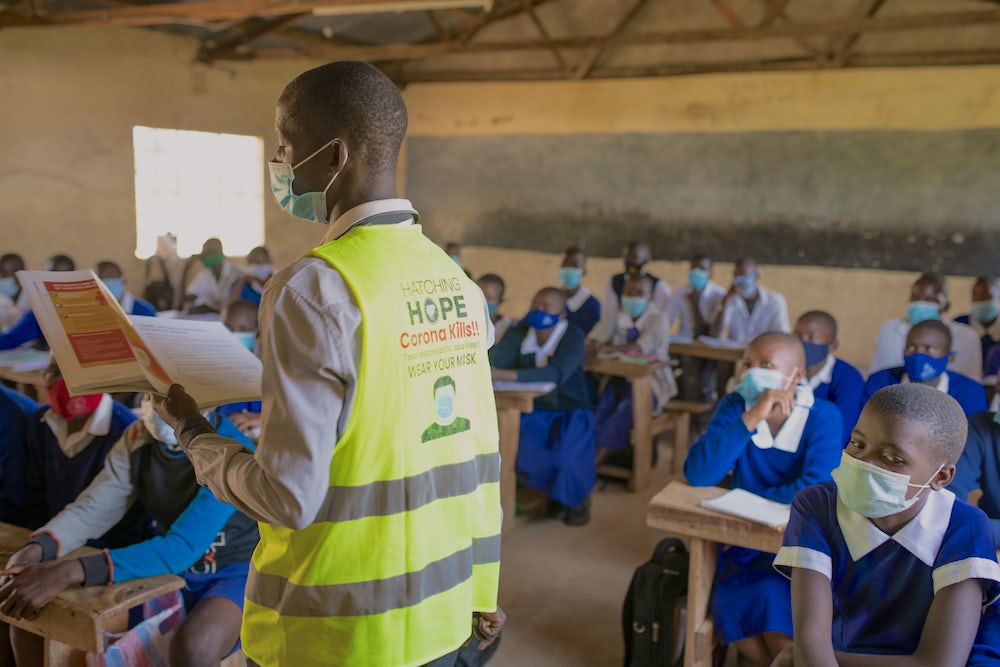 A man wearing a Hatching Hope vest teaches the benefits of eggs to a classroom of kids.