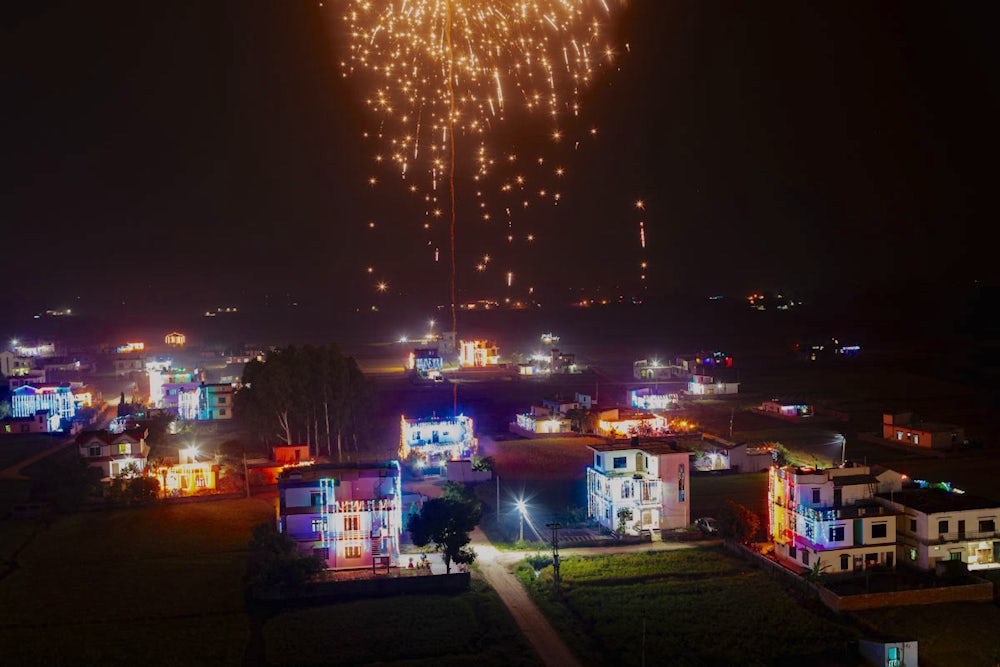 A firework rains down over a city at night.