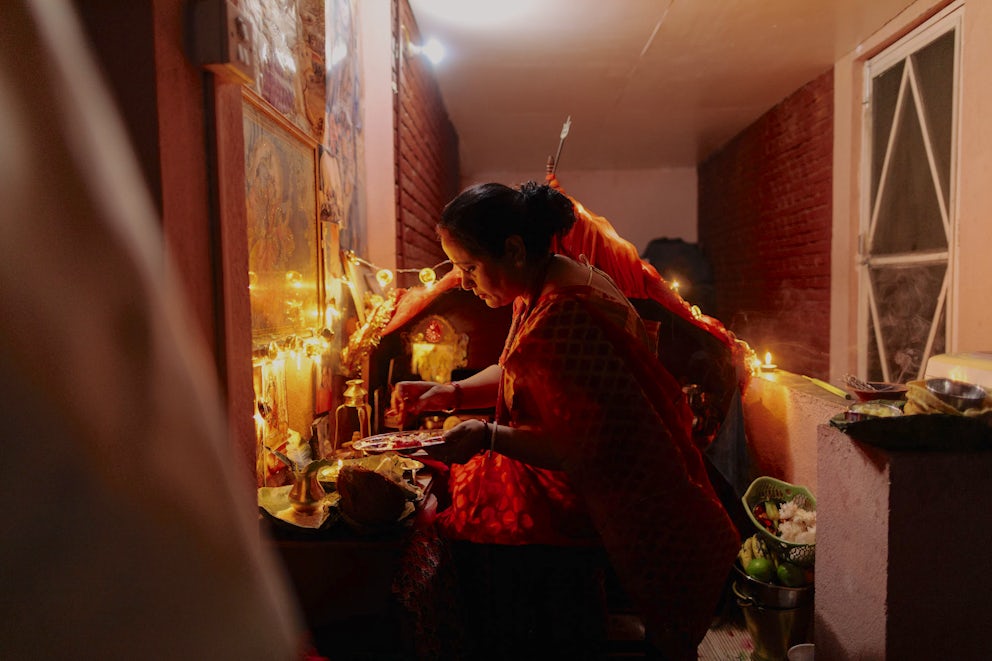 A Nepali woman lights a candle in her home.