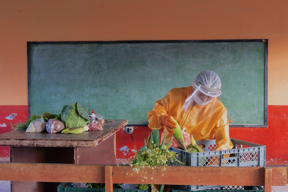 A worker packages a basket of produce for delivery.