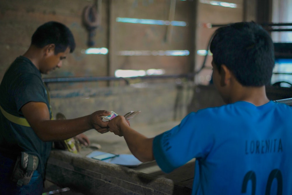 Two Guatemalan spice farmers exchange money.