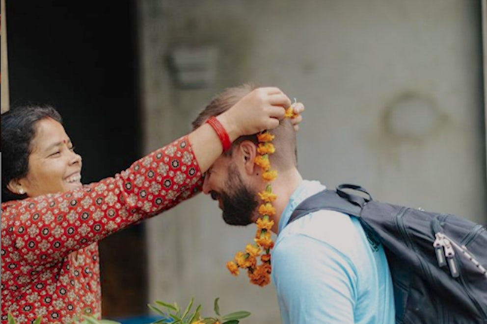 A man is greeted by a Nepali woman with marigolds in Nepal