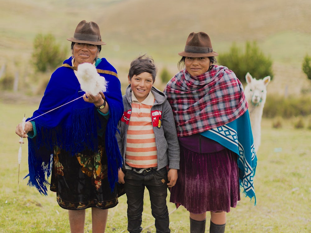 An alpaca sneaks in a family photo of María Juana Chaluisa (49), her nephew Michael (10) and her daughter Inés.