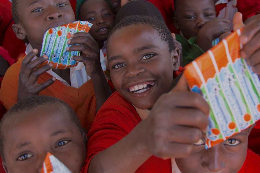 Children holding milk packets at school.