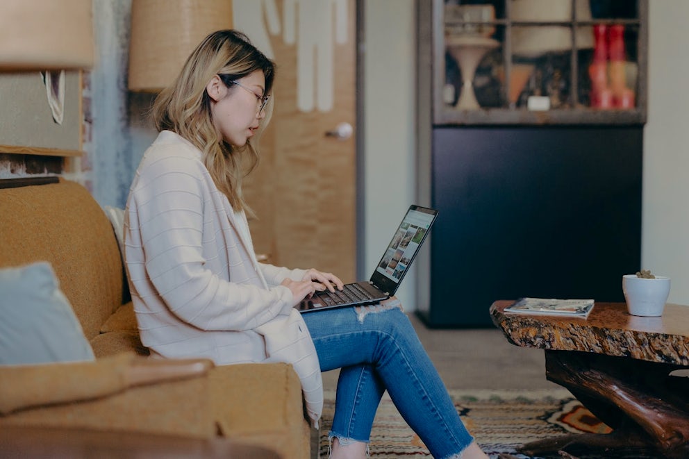 Woman sitting on couch on computer.