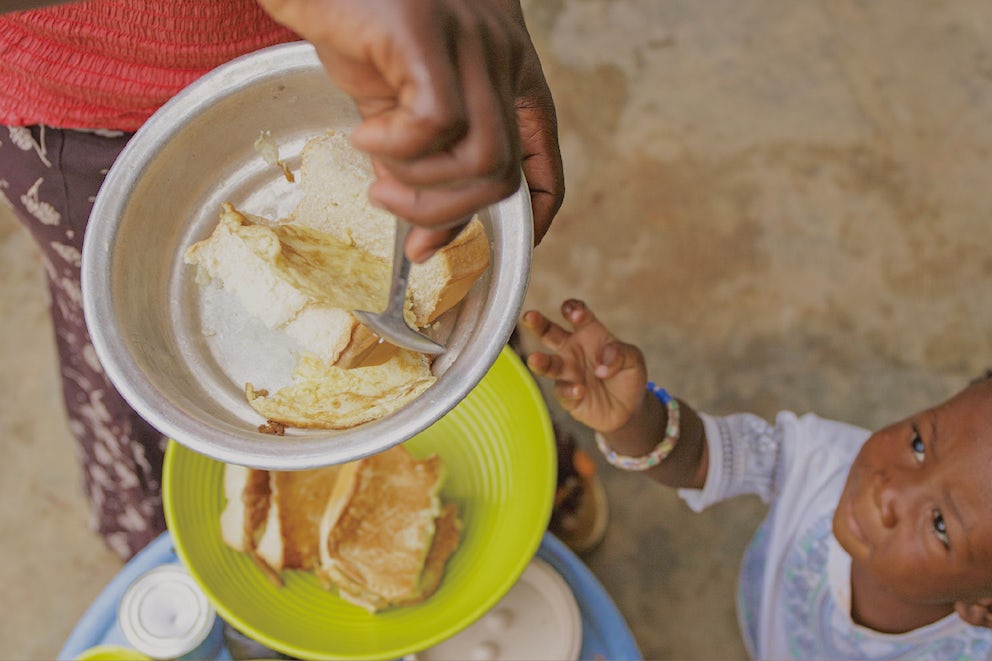 Child reaching for food on a plate.